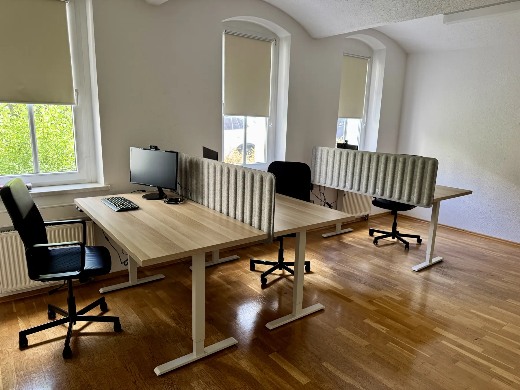 Heller Coworking-Raum mit höhenverstellbaren Schreibtischen und Parkettboden
